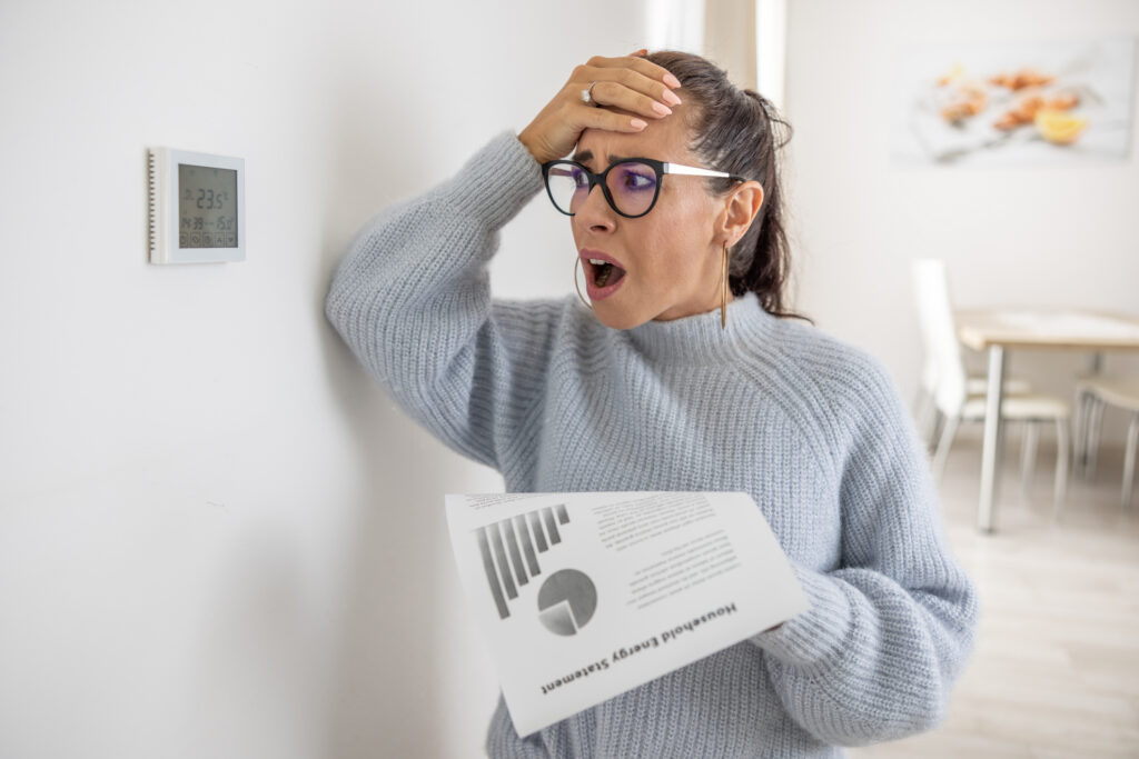 Homeowner looking at heating bill and thermostat